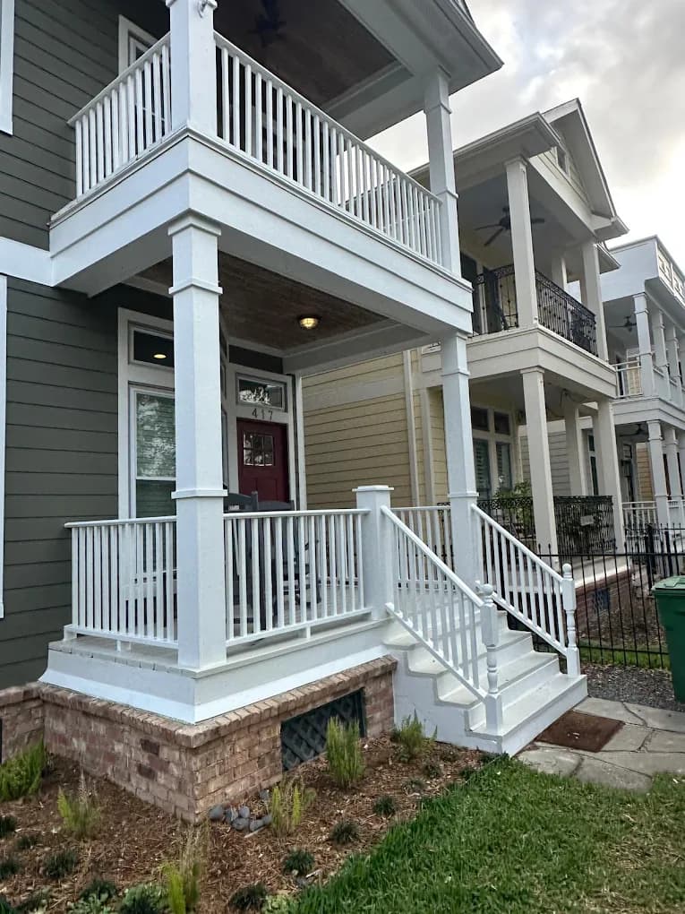 Two-story home exterior with a columned front porch and a second-floor balcony with white railings.