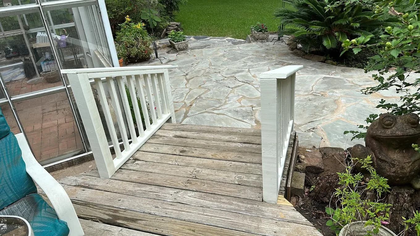 Backyard wood deck with an adjoining flagstone patio, a white railing, and landscaped beds.