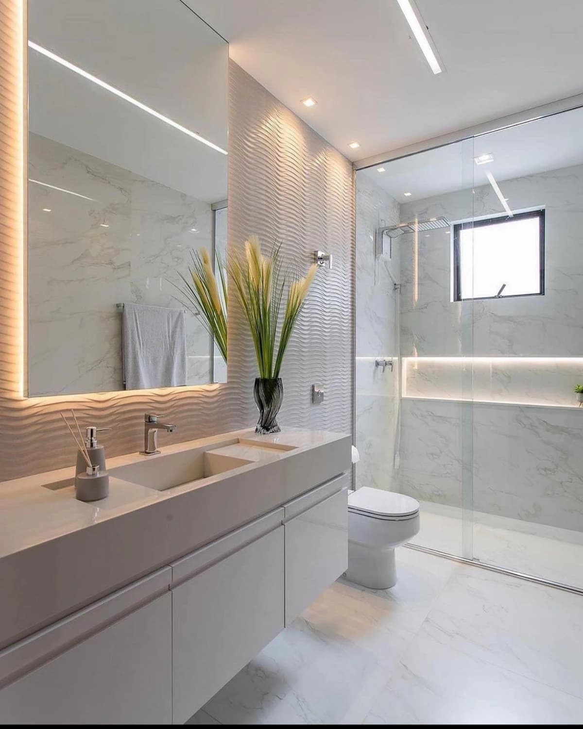 Modern bathroom with a floating wood vanity, a backlit mirror, a textured feature wall, and a glass shower.