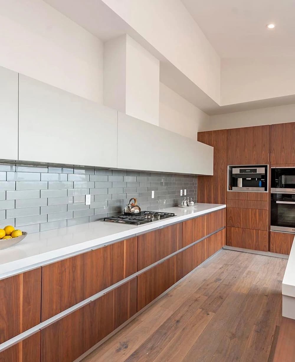 Walnut wood-slab kitchen cabinets with white quartz counters, a gray glass-tile backsplash, and a gas cooktop.