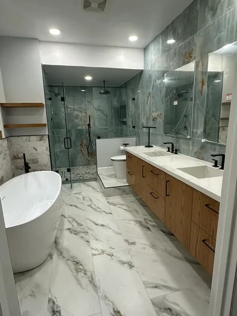 Bathroom with a freestanding tub, a green-quartzite walk-in shower, a wood double vanity with white marble counters, and marble-look tile floors.