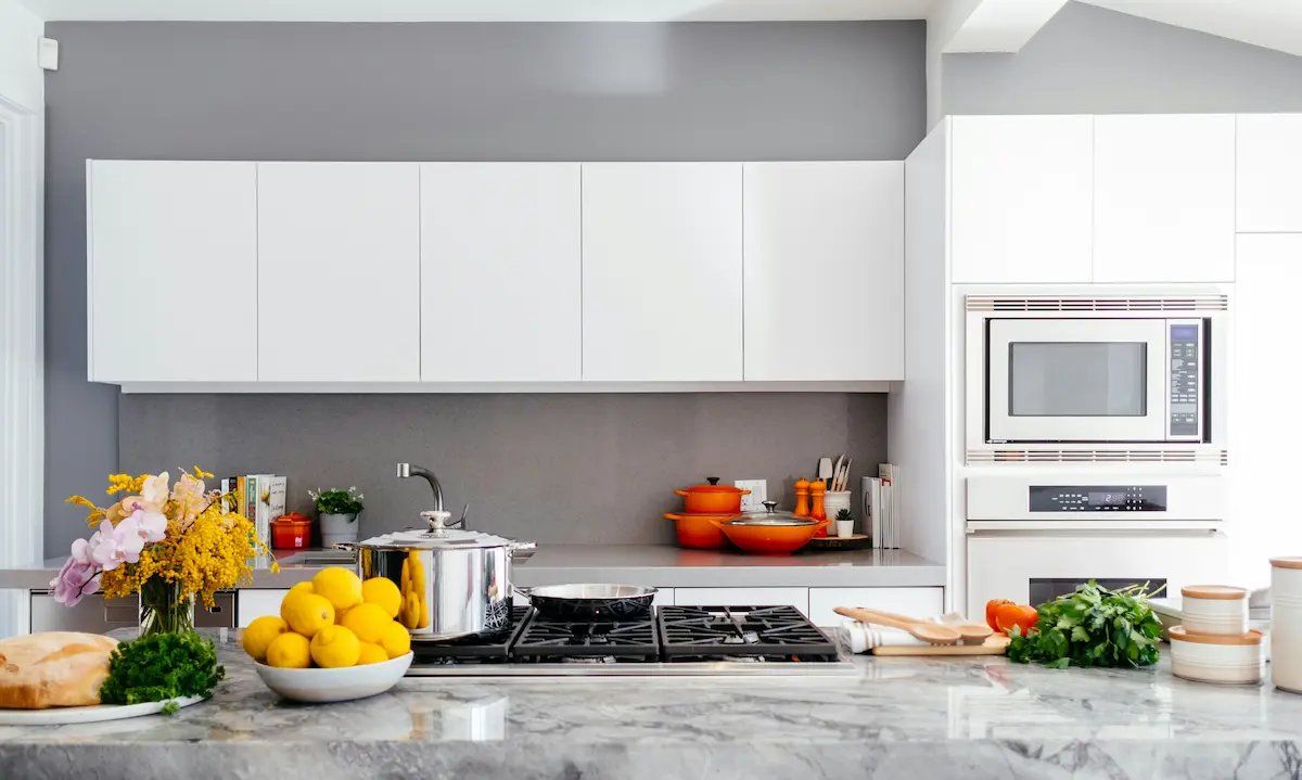 Bright white kitchen with flat-panel cabinets, a gas cooktop, and a marble-look stone island.
